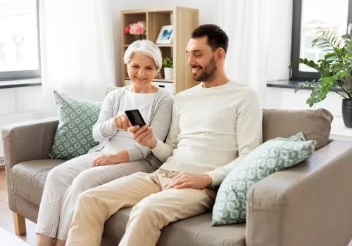 A grandmother being shown by her grandson how to play solitaire using their mobile phone